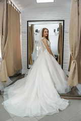 Fototapeta na wymiar Happy bride in salon posing in wedding dress
