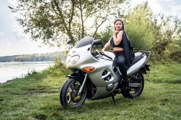 Fototapeta na wymiar Beautiful girl with long hair posing at a motorcycle