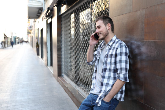 Happy Man Talks On Phone Leaning On A Wall In The Street