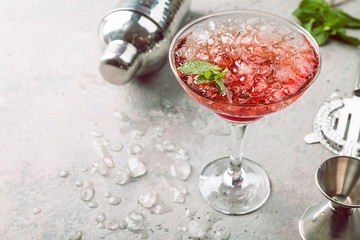 Fresh red margarita cocktail with ice and mint over gray background