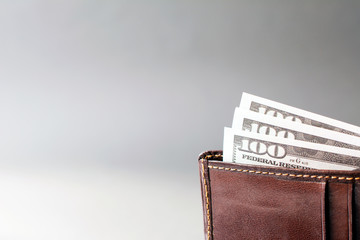 brown leather wallet with money dollars on a gray background