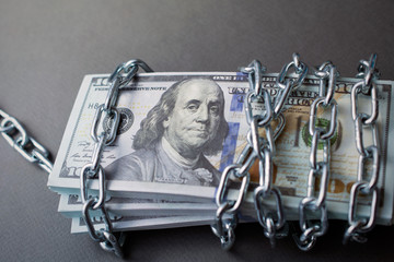 chained money, bundle of dollars tied up with a chain, the concept of debt, frozen assets. dark...