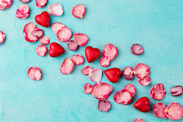 Chocolate heart and lips shaped candies with rose candied sugared petals. Blue background. Top view.