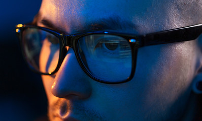 vision, hacking and technology concept - close up of hacker eyes in glasses looking at computer...