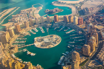 Rich real estate Pearl-Qatar island in Doha through the airplane porthole, aerial view