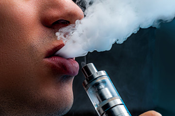 Close-up - young man vaping e-cigarette
