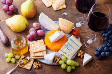 Assortment of cheese, grapes with red wine in glasses. Wooden background. Top view.