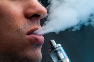 Close-up - young man vaping e-cigarette