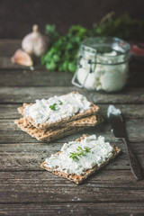 Crispbread toast with homemade herb and garlic cottage cheese on wooden background