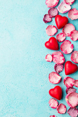 Chocolate heart shaped candies with rose candied sugared petals. Blue background. Top view. Copy space.