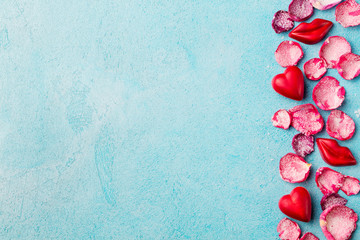 Chocolate heart and lips shaped candies with rose candied sugared petals. Blue background. Top view. Copy space.