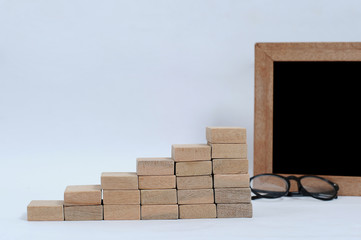 Business concept for growth success process. Wood block stacking as step stair. Glasses and blackboard