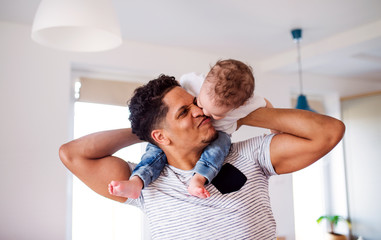 Father and small toddler son indoors at home, playing.