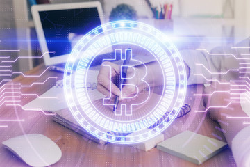 Cryptocurrency hologram, bitcoin, ico theme over hands taking notes background. Concept of blockchain. Multi exposure