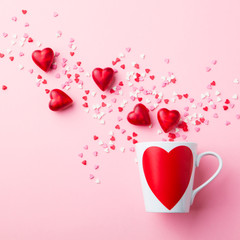 Mug with sugar and chocolate hearts on pink background. Flat lay composition. Romantic, St Valentines Day concept.