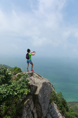 Successful Woman Hiker taking picture with smartphone In Seaside Mountain Top