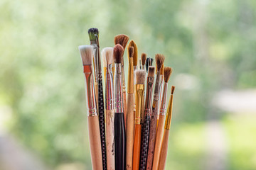 Painter used brushes on green nature backgroung, many different and dirty instruments of the artist.
