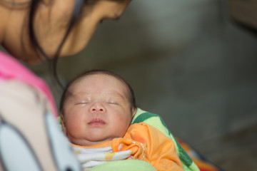 Asian mothers are holding a newborn baby at home.