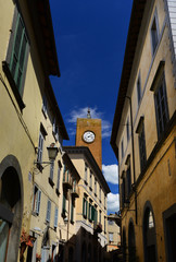 Fototapeta na wymiar Medieval Torre del Moro (Moro Tower) with old clock, one of Orvieto landmarks seen from the city center narrow street