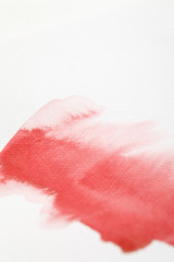 close up view of red watercolor paint spill on white background