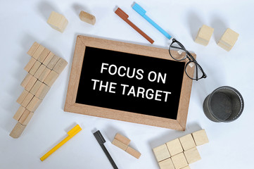 FOCUS ON THE TARGET text on blackboard with office accessories. Business motivation, inspiration concepts, pen and pencil case, wood block stacking as step stair symbol of business concept