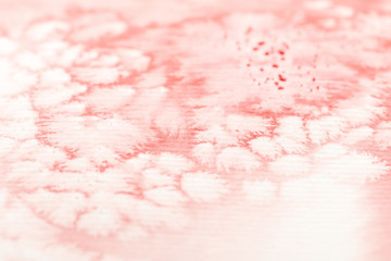 close up view of red watercolor paint spill on textured white paper background