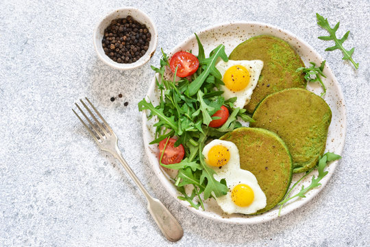 Morning breakfast: pancakes with spinach, salad and egg on the kitchen table. View from above.