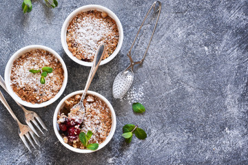Cherry crumble with nuts and mint on a concrete background.