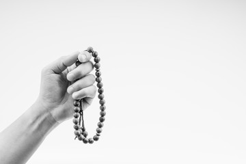 Hand holding a muslim rosary beads or Tasbih on black and white. Copy space and selective focus