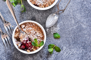 Cherry crumble with nuts and mint on a concrete background.