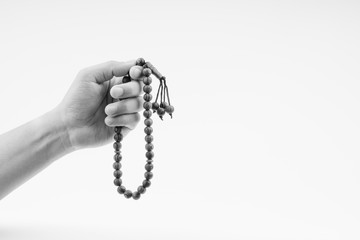 Hand holding a muslim rosary beads or Tasbih on black and white. Copy space and selective focus