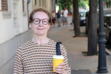 Cute mature woman holding coffee cup outdoors