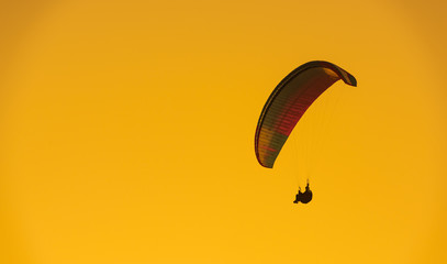 Colorful paragliding. Orange color dramatic sky. Summer background
