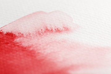 close up view of pale red watercolor paint spill on white background