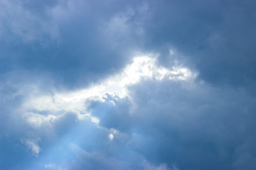 Naklejka na ściany i meble Breaking rays of sunlight through puffy clouds