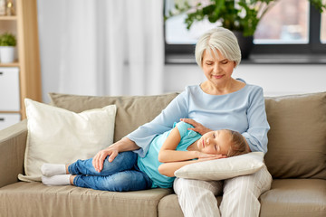 family, generation and people concept - happy smiling grandmother and granddaughter sleeping on...