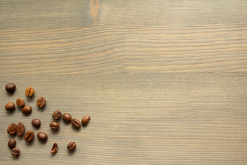 Handfuls of coffee beans scattered on the background of raw wood. A pinch of coffee. Background for text for your coffee house or bakery.