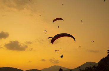 Silhouette paragliding. Sunset with dramatic sky. Summer background