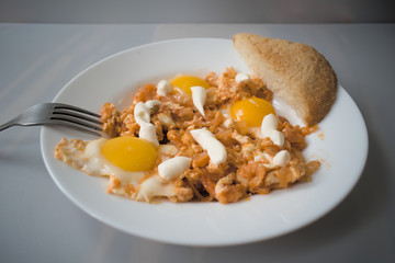 Fried eggs with meat, onions and tomatoes. The prepared dish combines the aromatic and taste qualities of European cuisine.