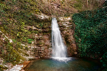 Fototapeta premium Beautiful waterfall and red stones combined with a small lake on the mountainside.