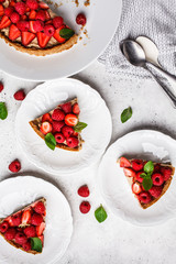Pieces of berry tart with raspberries, strawberries and cream, top view.