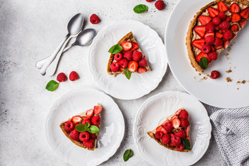 Pieces of berry tart with raspberries, strawberries and cream, top view.