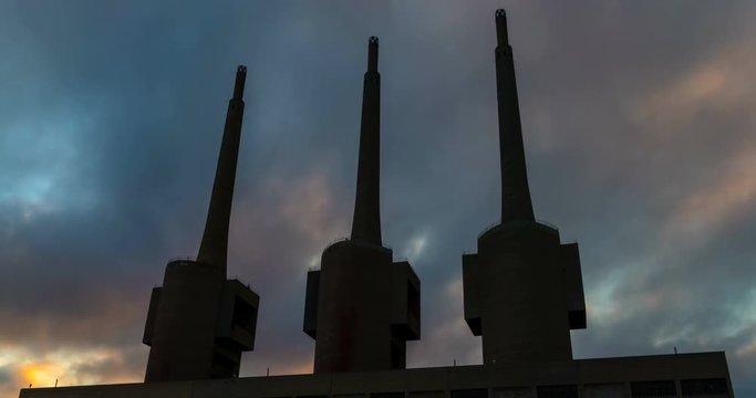 Ancient thermal power station in Sant Adria, province of Barcelona.Hyper Lapse. Silhouette of three chimneys with clouds in motion on sunset sky background. Smooth camera movement: Panning right.