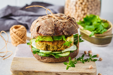 Vegan sandwich with chickpea patty, avocado, cucumber and greens in rye bread.