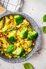 Vegetarian pasta with broccoli, asparagus and chickpeas in pan, top view.