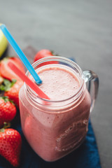 Smoothie with strawberry and banana in the jar at dark background