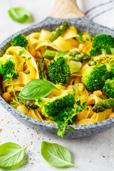 Vegetarian pasta with broccoli, asparagus and chickpeas in pan.
