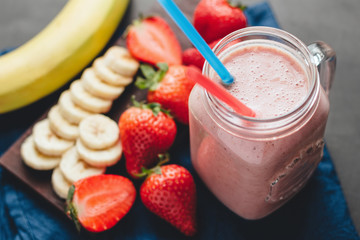 Smoothie with strawberry and banana in the jar at dark background