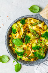 Vegetarian pasta with broccoli, asparagus and chickpeas in pan, top view.