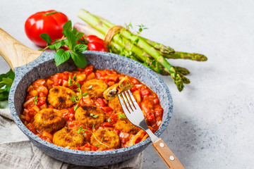 Vegetarian vegetable meatballs with tomato sauce in frying pan.
